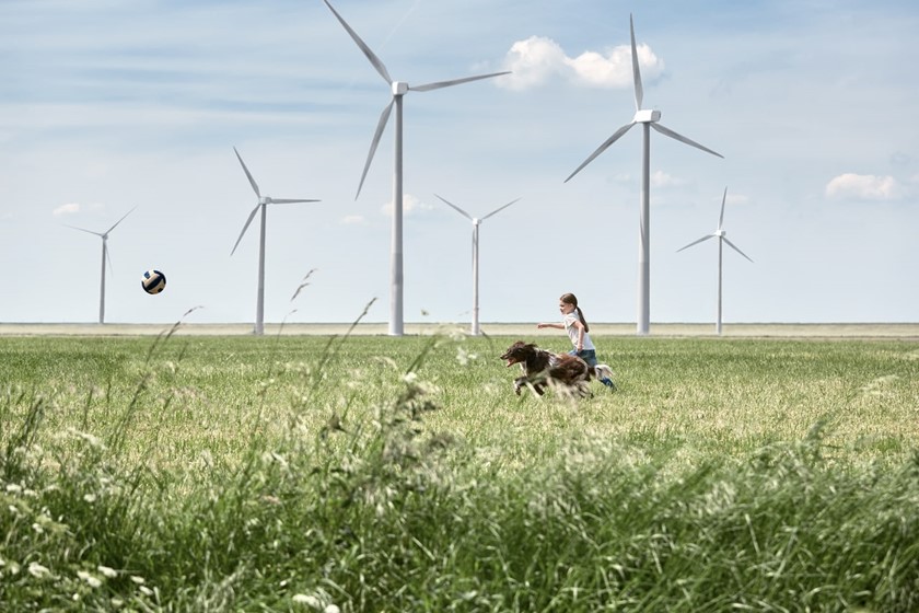 Meisje met hond en windmolen: In 2023  100% groene stroom uit Nederland voor onze klanten thuis en in het mkb 