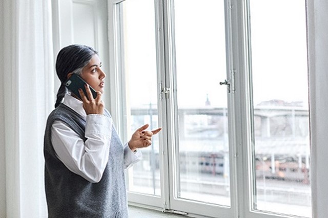 Vrouw staat voor het raam te bellen voor de Energiescan l Vattenfall energie