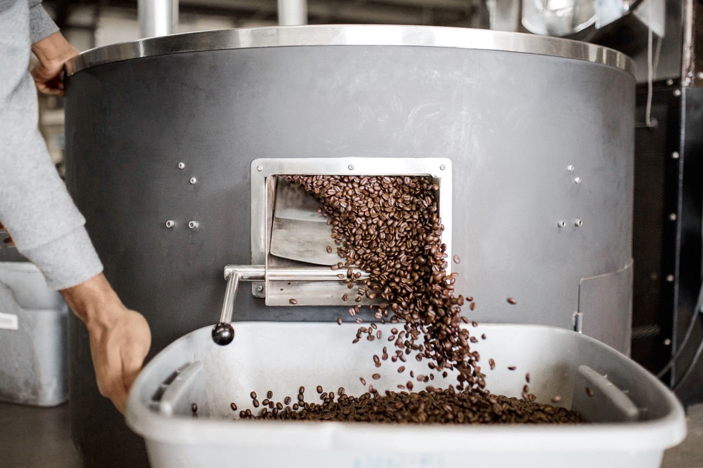 Koffiebonen vallen uit een brander in een container