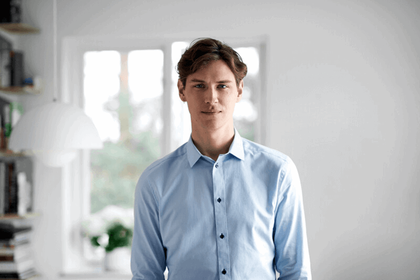 Zelfstandig ondernemer staat in zijn werkruimte in huis en is blij met inzicht in energieverbruik via de Energie-app