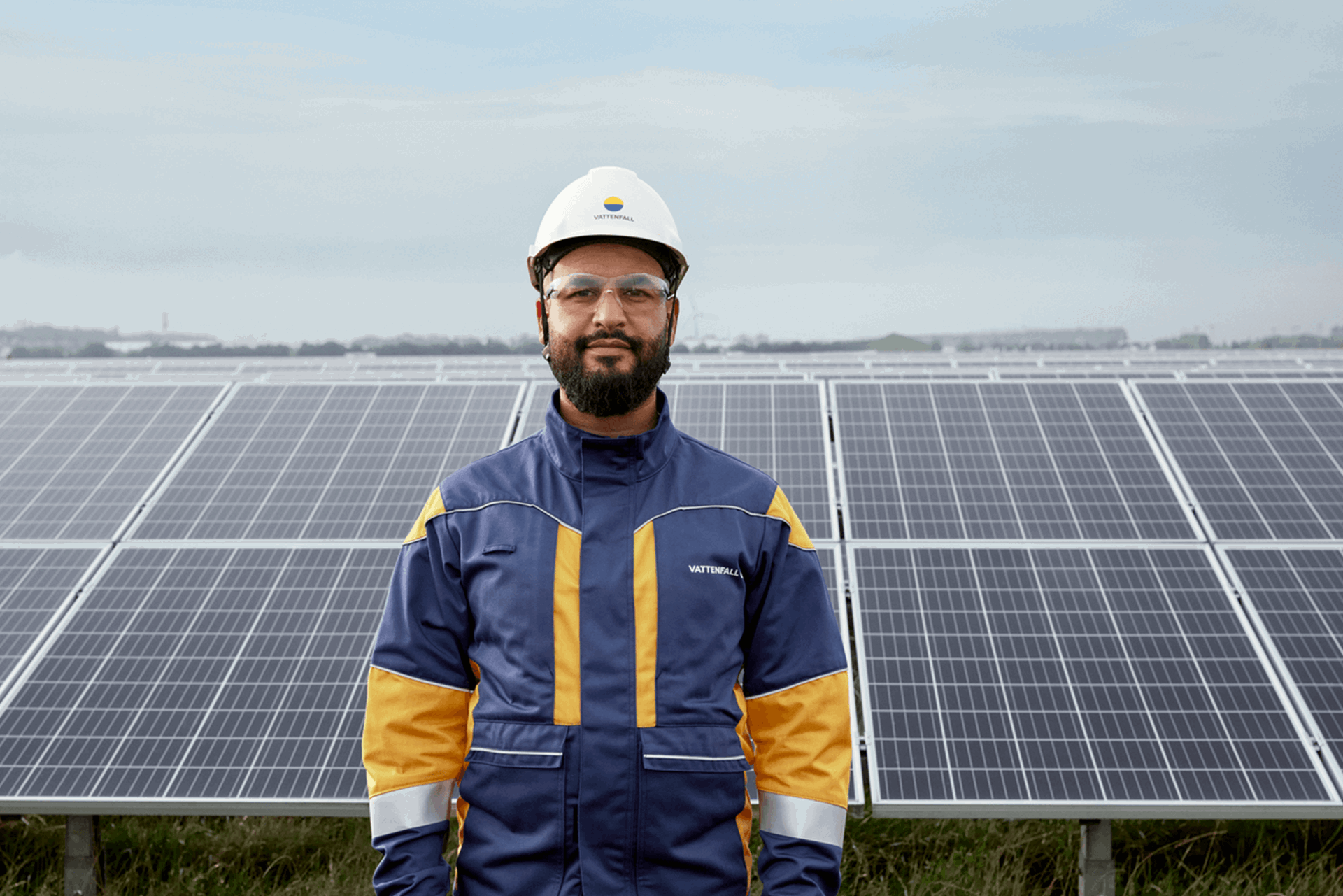 Zonnepanelen op een zonneweide met windmolens op de achtergrond