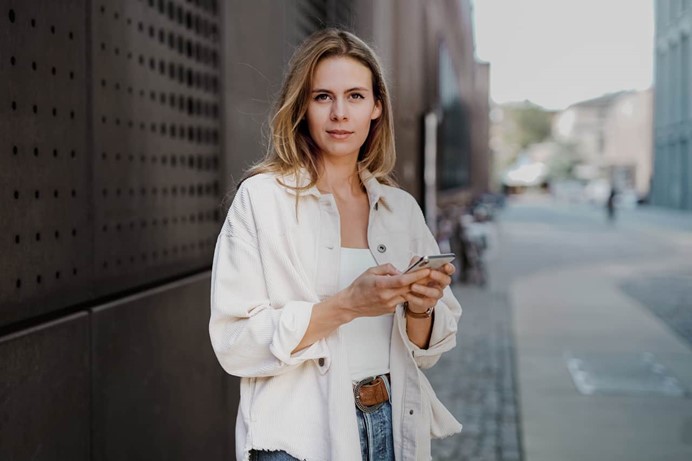 Vrouw-staat-buiten-met-haar-mobiel-om-inzicht-te-krijgen-in-verbruik