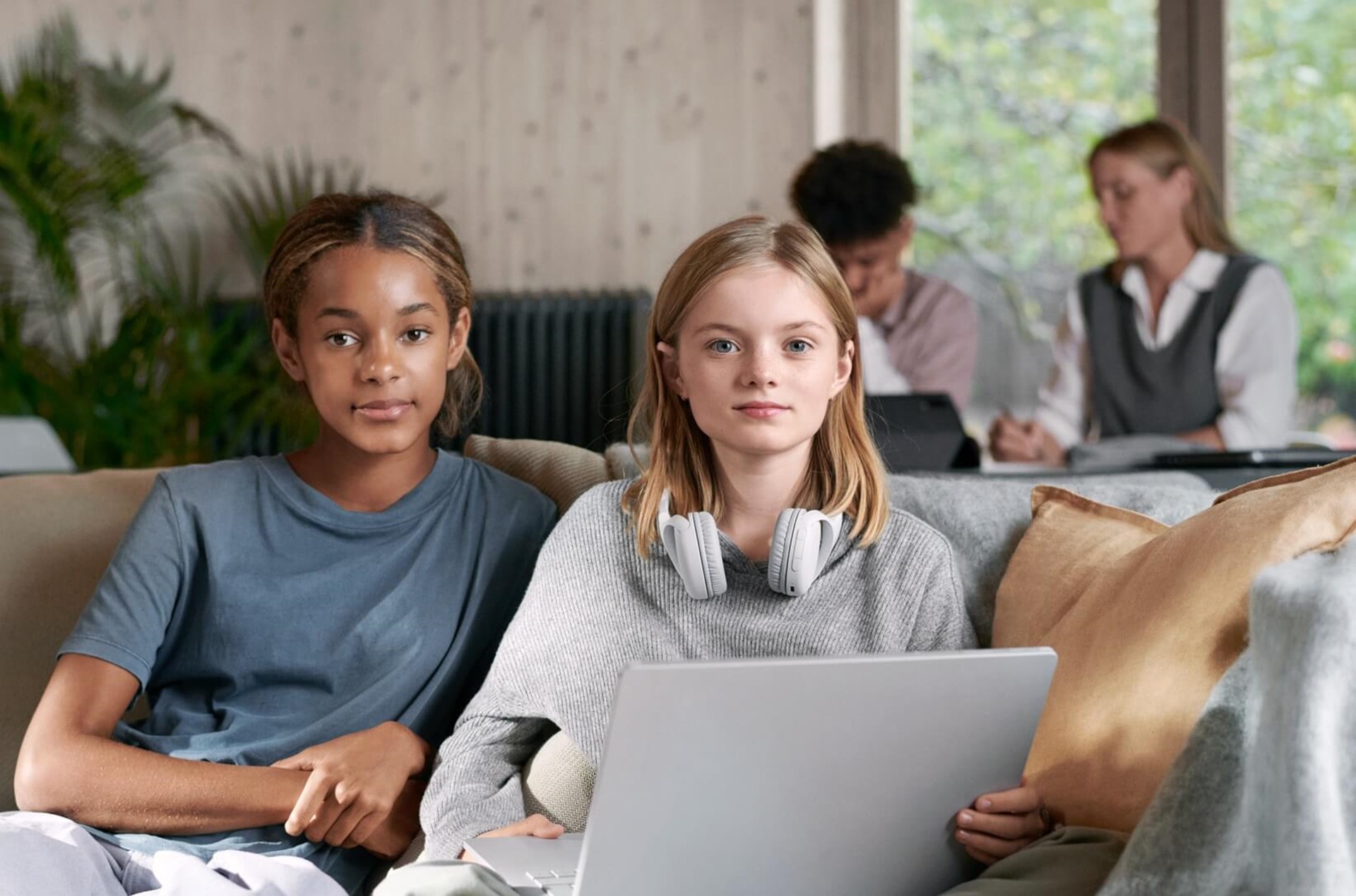 Twee slimme meiden zitten op de bank en werken op de laptop | Vattenfall energie