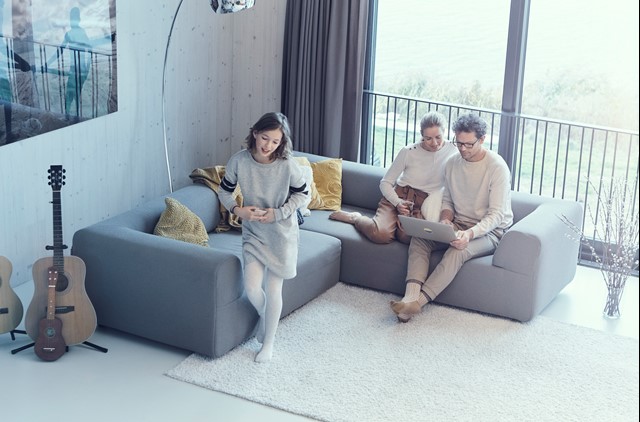 Gezin op de bank, blij kijkend naar de laptop | Vattenfall warmte-energie