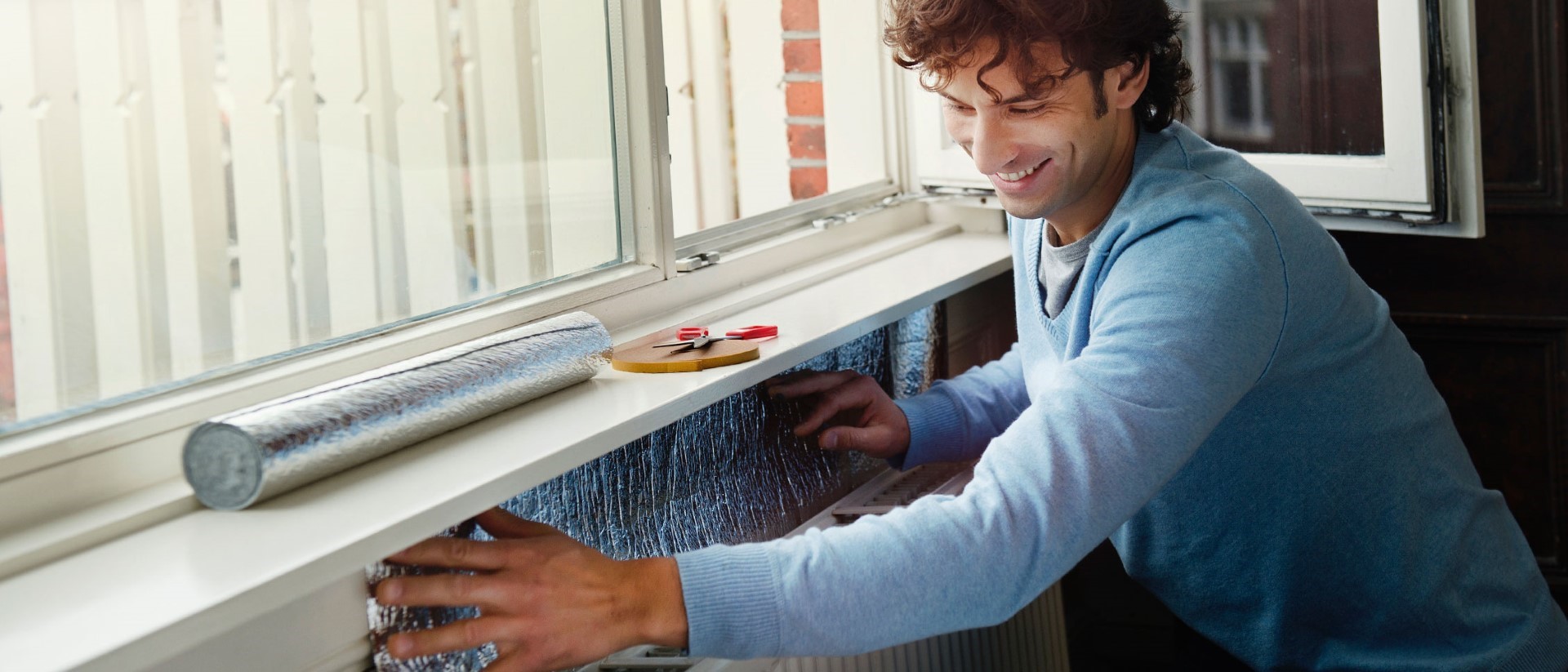 Huis isoleren | Man brengt radiatorfolie aan