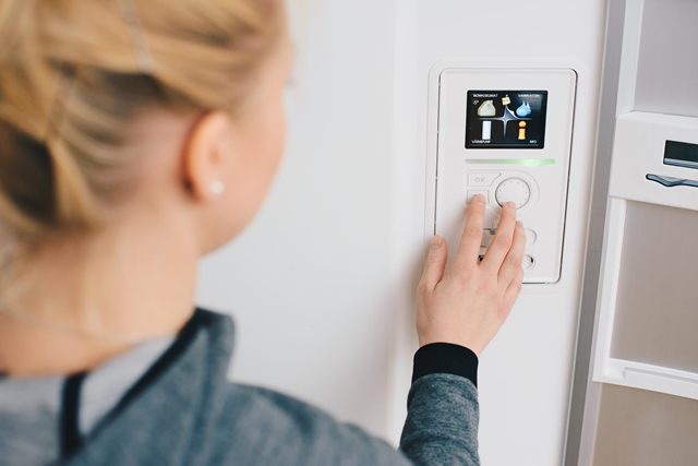 Jonge vrouw bedient de knoppen van een warmtepomp | Vattenfall over warmtepomp met zonneboiler