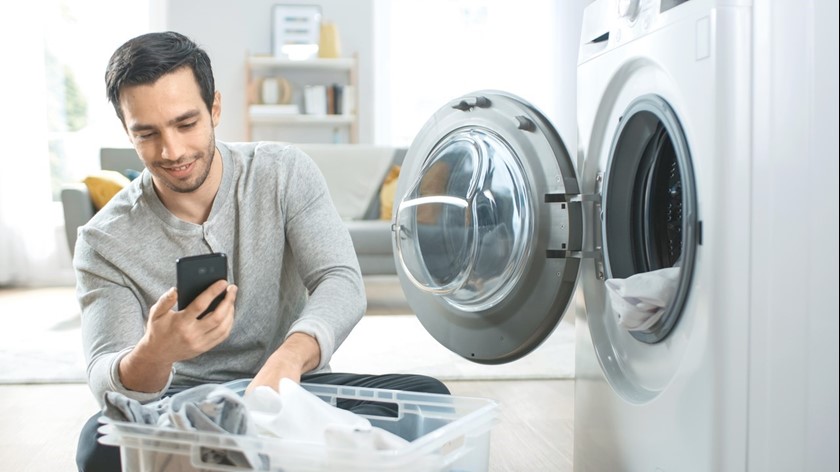 Man met telefoon en wasmachine | Vattenfall dynamisch energiecontract 