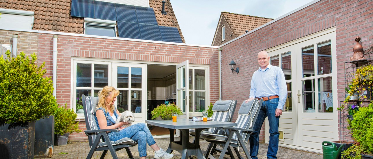 Familie van der Voort in hun tuin met op het huis zonnepanelen