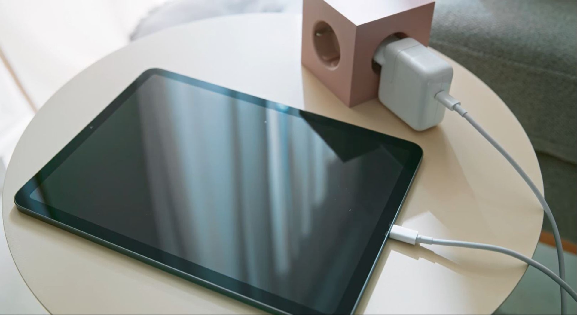 Een tablet laadt op met oplader in stopcontact