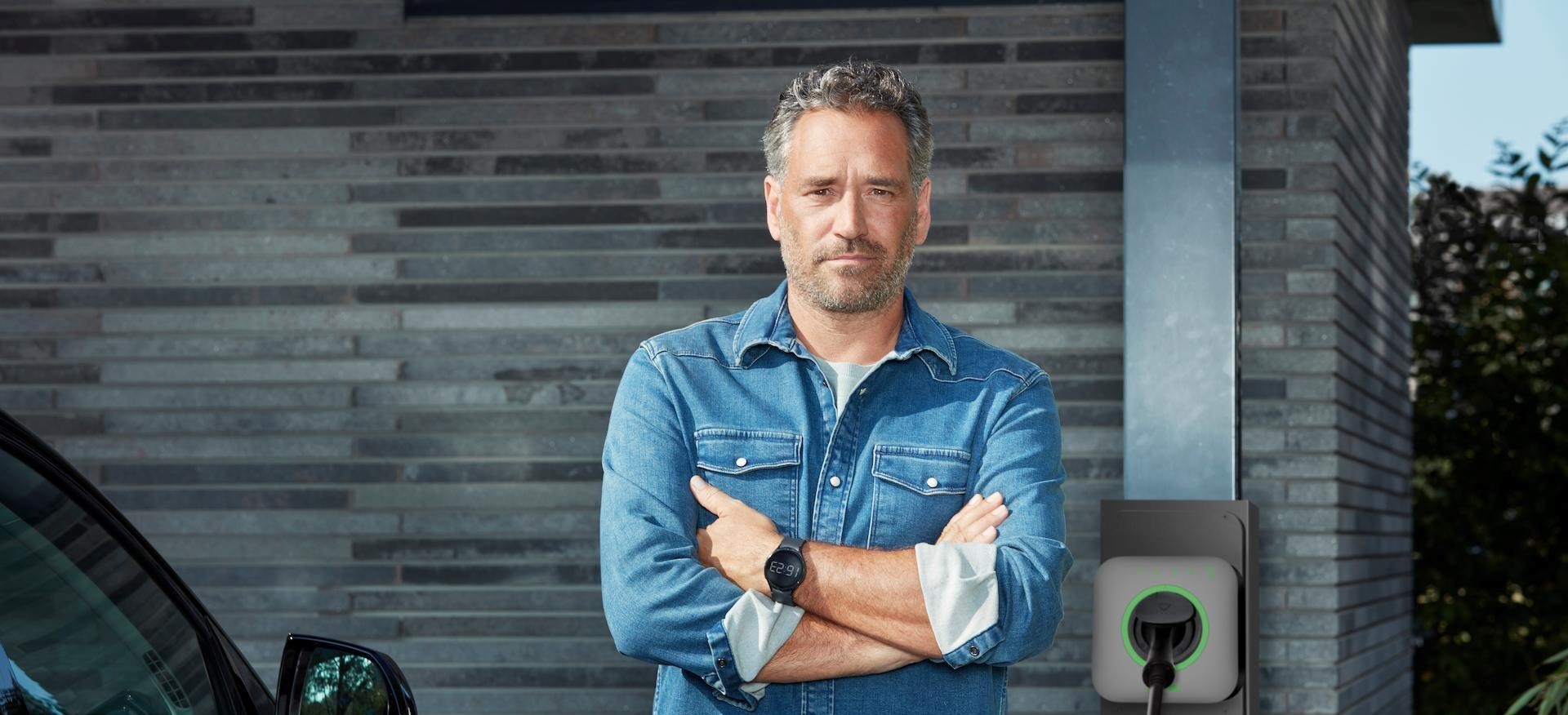 Meneer laad auto op met laadpaal voor thuis