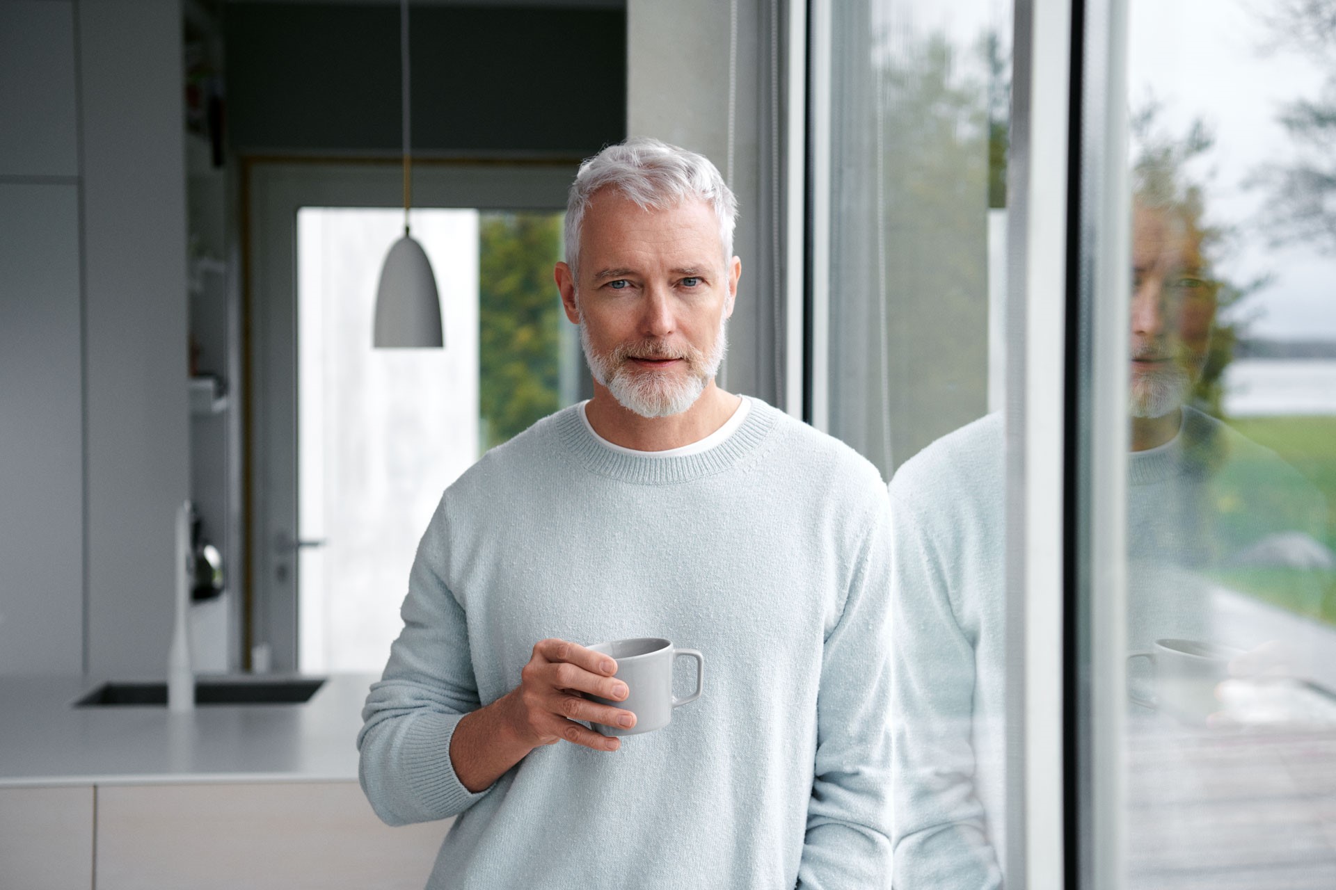 Man bij glazen deur met koffie