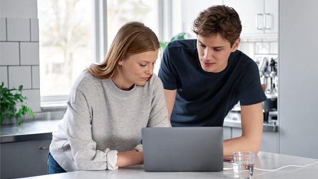 Vrouw en man kijken op laptop in keuken