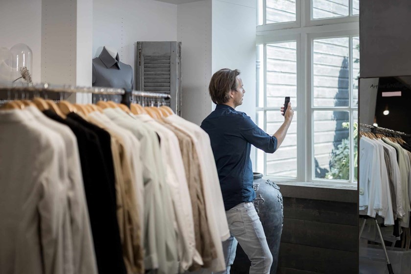Een ondernemer met een eigen winkel videobelt tussen de kledingrekken