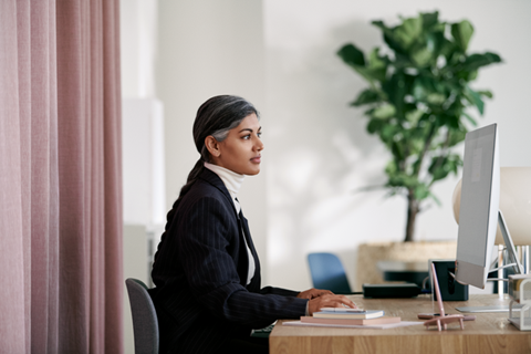 Vrouw staat met een laptop op het werk en lacht
