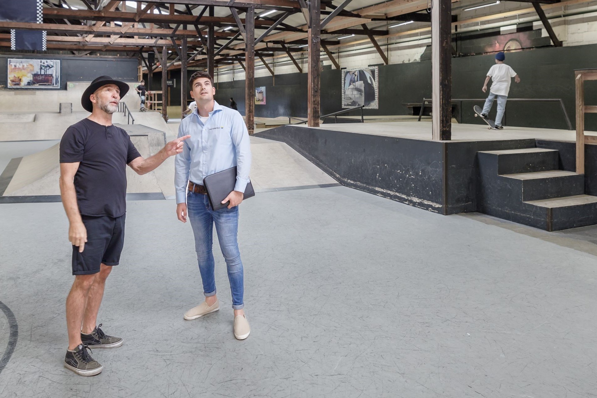 Een ondernemer en een adviseur staan in een bedrijfshal te overleggen - Je energiepartner bij besparen