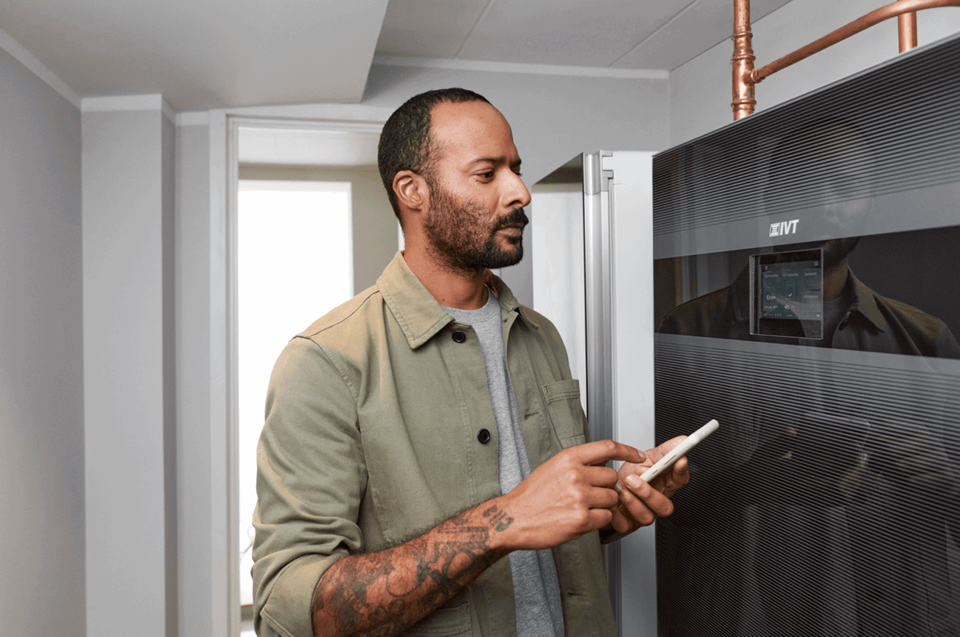 Man staat met mobiel bij zijn warmte installatie - Prijsplafond op jaarafrekening