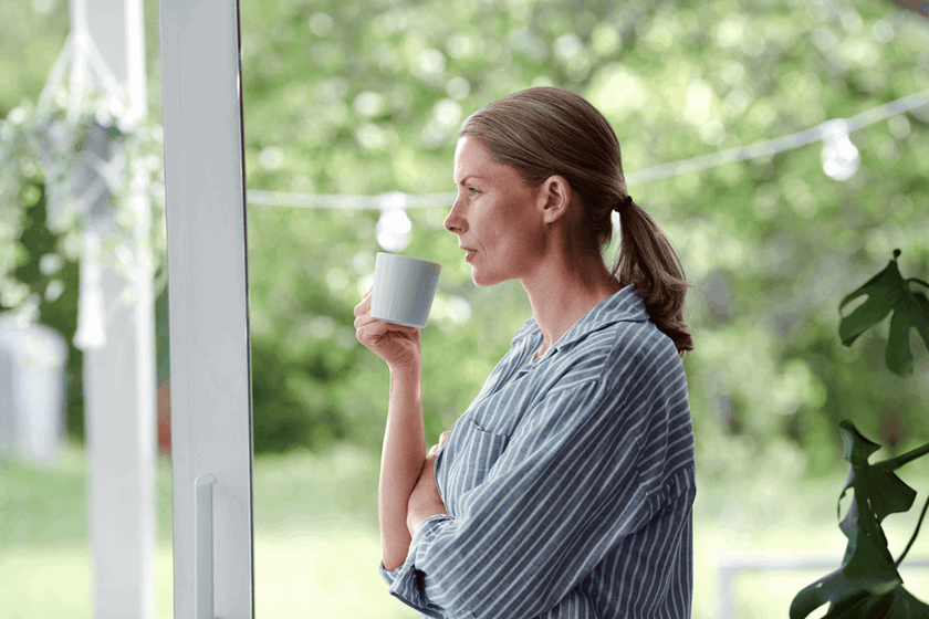 Vrouw met kop thee bij raam