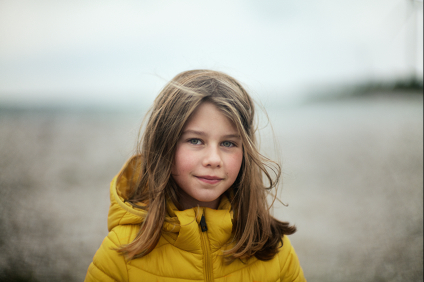 Meisje op het strand met warme jas aan